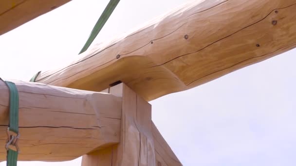 Primer plano de una parte del edificio de madera en construcción, vista inferior. Clip. Casa con marco de madera, vigas de madera sobre fondo cielo nublado, carpintería . — Vídeos de Stock