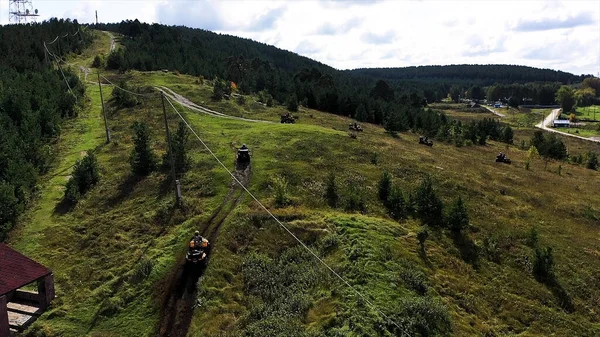 Bovenaanzicht vanuit de lucht van racers op een quad motor op het platteland door het modderige parcours op de groene weide. Voorraadbeelden. Quad fietsen op een landweggetje. — Stockfoto