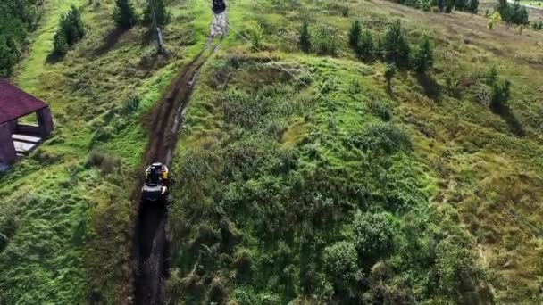 Bovenaanzicht vanuit de lucht van racers op een quad motor op het platteland door het modderige parcours op de groene weide. Voorraadbeelden. Quad fietsen op een landweggetje. — Stockvideo