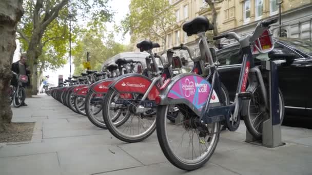 Londres, Reino Unido - septiembre de 2019: Bicycle Parking en Londres. Acción. Bicicletas en la estación de acoplamiento con personas caminando por la pasarela, Londres — Vídeo de stock