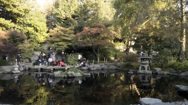Londra 'da küçük bir göleti ve yeşil ağaçlar üzerinde yürüyen aileleri olan güzel bir milli park. Başla. Su yüzeyindeki insanların yansımasıyla çevrili küçük bir gölet..
