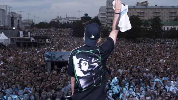 Russia - Yekaterinburg, 08.15.2019: Back view of a young man in front of cheering audience at rock concert. Action. Singer is trying to rock the public, art and music concept. — Stock Photo, Image