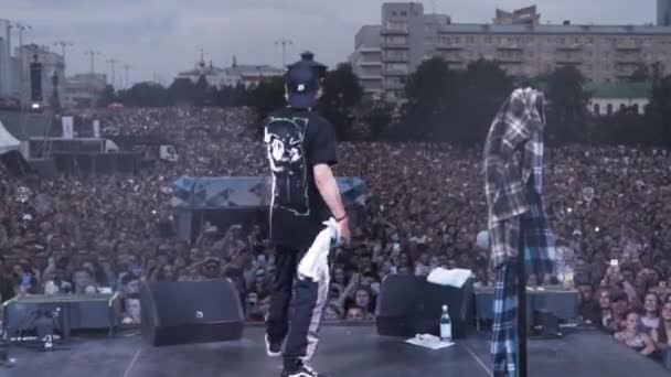 Rosja - Moskwa, 08.15.2019: Widok z tyłu młodego człowieka przed dopingującą publicznością na koncercie rockowym. Akcja. Singer stara się rozbujać publiczność, sztukę i muzykę. — Wideo stockowe