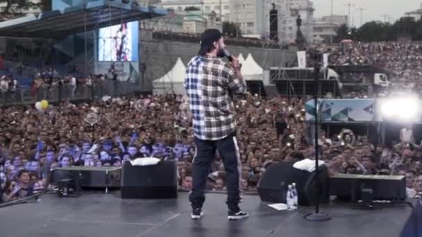 Rusia - Moscú, 10.02.2019: concierto ruso de hip hop y rap con un líder y fanáticos de la animación. Acción. Vista trasera de un joven artista actuando en el escenario al aire libre . — Vídeos de Stock