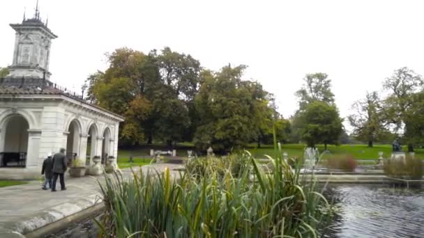 Beautiful green Park with fountains in cloudy weather. Action. Large old Park with pond and fountains on background of walking tourists in cloudy weather — Stockvideo