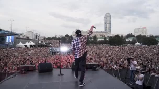 Rusia - Ekaterimburgo, 08.15.2019: Una gran multitud de fans viendo rapero ruso actuando en vivo en el escenario. Acción. Joven artista frente a sus fans . — Vídeo de stock