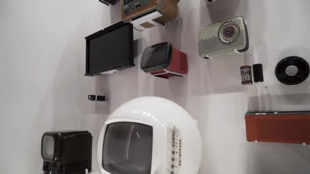 The exhibition of vintage tv-receivers, old audio players and radio in the museum of vintage technology. Action. Retro electronic devices hanging on the wall in the gallery. — Stock Video