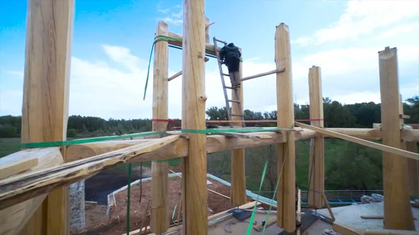Homme constructeur au travail avec la construction de murs en bois dans la campagne. Clip. Homme charpentier sur la construction inachevée d'une maison en bois . — Photo
