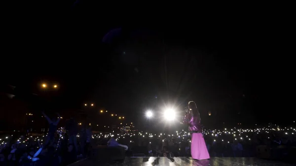 stock image Czech Republic, Prague - 09.05.2019: rear view of a young woman singer performing on the stage in bright pink dress. Action. Dark background with many cheering fans and shining lights, music and art