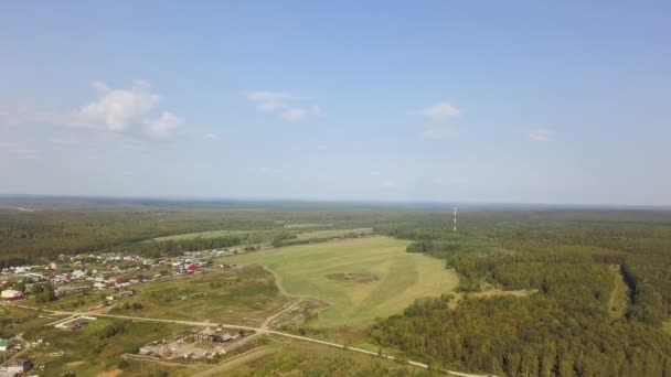 Aerial view of outback and typical old village in forest. Stock footage. Top view of houses among green trees near the meadow, summer landscape. — Stockvideo