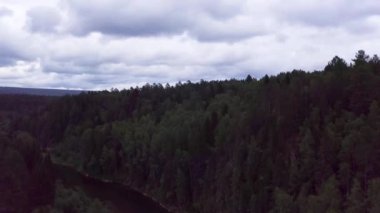 Yoğun kozalaklı ormanda yaz akşamının hava manzarası ve bulutlu arka planda dar bir nehir. Stok görüntüleri. Yeşil yaz doğası, çam ağaçları ve çalılar.