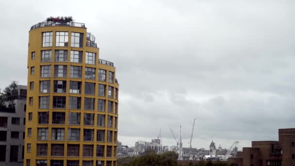 Mehrstöckiges Wohnhaus mit moderner Architektur vor dem Hintergrund der Stadt. Aktion. modernes Design-Wohnhaus im Hintergrund der Stadt im Bau bei trübem Wetter — Stockvideo