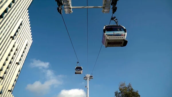 Modern cable car with cabins on blue sky background. Action. Beautiful cable car with modern cabins and beautiful design on sky background — Stock Photo, Image