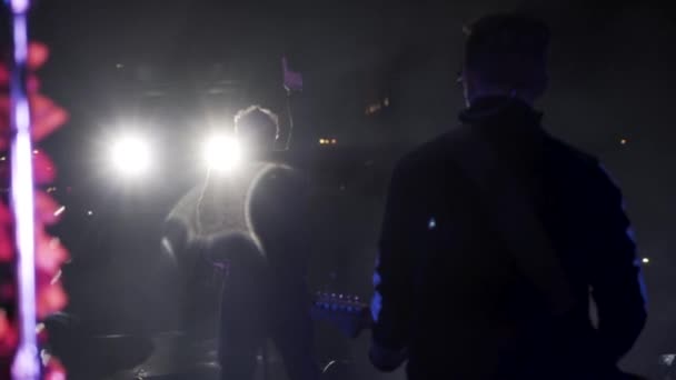 Moskau, russland - 20.11.2019: Rückansicht eines Gitarristen und eines Frontmannes auf der Konzertbühne im dunklen Raum. Aktion. Scheinwerfer und eine Musikkapelle während des Konzerts. — Stockvideo