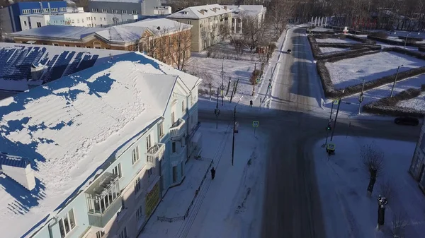 Vue aérienne de la petite ville en hiver avec une route enneigée et une voiture de conduite. Images d'archives. Vie calme dans une belle ville, de nombreuses maisons et bâtiments couverts de neige . — Photo