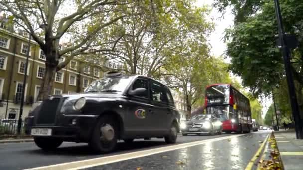 Londra, İngiltere-Eylül 2019: Eski ev ve binaların arka planında turist kırmızı otobüsü bulunan şehir trafiği. Başla. Kırmızı otobüs yurtdışına seyahat eden turistler için mıknatıs — Stok video