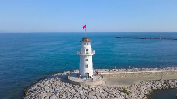 Vue aérienne du phare près de l'océan bleu. L'art. Belle balise blanche avec des touristes marchant et ciel clair avec l'horizon sur le fond . — Video