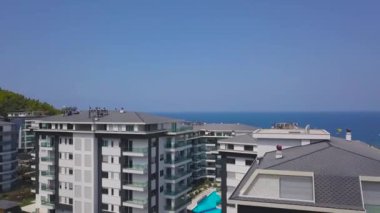 Deniz kenarındaki bir yaz mevsiminde temiz mavi suyu olan güzel bir yüzme havuzunun havadan görünüşü. - Sanat. Yeşil çimenler ve diğer evlerle çevrili otel binaları.