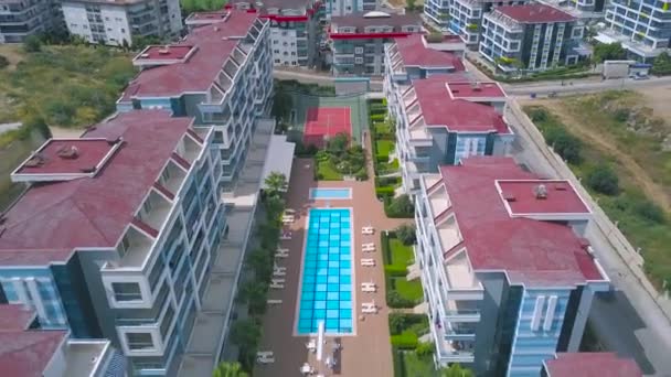 Vista aérea de arriba hacia abajo de los hoteles con piscina con agua azul rodeada de otros edificios y césped verde. Art. Vacaciones de verano en hotel de lujo . — Vídeos de Stock