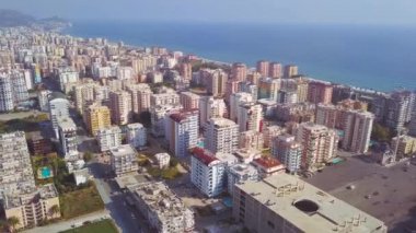 Güneşli bir yaz gününde mavi sonsuz okyanus kıyısındaki büyük şehir üzerinde harika bir insansız hava aracı uçuşu. - Sanat. Mavi gökyüzü arka planındaki caddelerin ve binaların havası.
