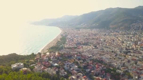 Vista aérea volando hacia la ciudad y una montaña contra el atardecer sobre el mar. Art. Increíble paisaje marino con luz solar reflejada en la superficie del agua . — Vídeo de stock