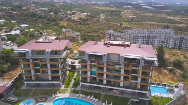 Aérea de la piscina con agua azul clara y zona de relax en el complejo. Art. Día soleado en la ciudad del sur, edificios altos y vegetación verde . — Vídeo de stock