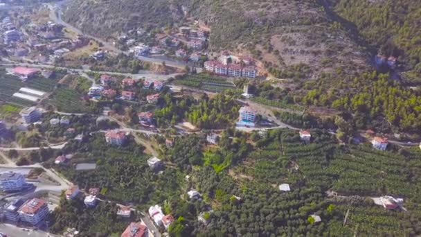 Vista aérea de la típica ciudad en las montañas. Art. Volando por encima de la ladera de la alta colina cubierta de verdes arbustos y árboles, casas, villas y carreteras . — Vídeo de stock