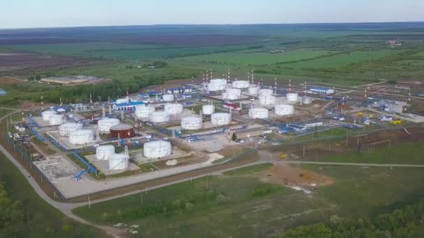 Vista aérea de grandes depósitos redondos blancos con tuberías azules entre césped verde en la planta de refinería de gas y petróleo. Clip. Fábrica de transbordadores, tanques y extracción de aceite con almacenamiento en el día soleado de verano . — Vídeo de stock