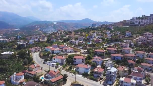 Prachtig uitzicht vanuit de lucht op de huizen op de heuvel met blauwe bewolkte lucht op de achtergrond. Kunst. Vakantiehuisjes en villa 's gelegen op de helling van groene beboste berg. — Stockvideo