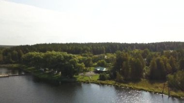 Kır nehri, ahşap iskele ve ağaçların arasında bir ev. Stok görüntüleri. Dinlenme merkezi olan ekolojik alanın havası, yaz doğası..