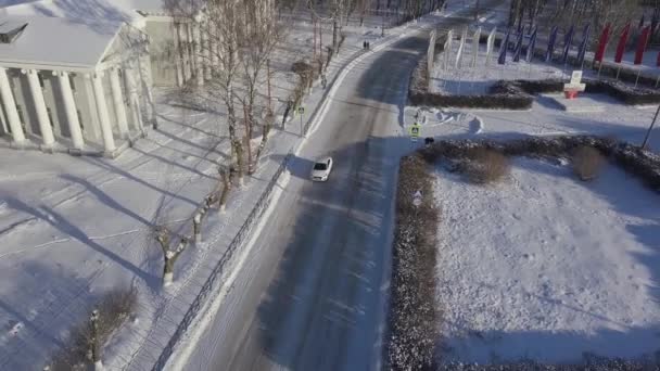 Luchtfoto van een eenzame witte auto die rijdt op de winterweg van een klein Russisch dorpje. Voorraadbeelden. Prachtige ijzige ochtend op het platteland. — Stockvideo