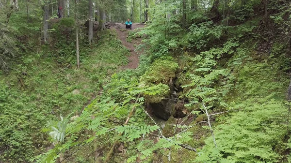 Homem usando capa de chuva azul sentado no chão na floresta verde da montanha. Imagens de stock. Homem caminhadas faz uma pausa para desfrutar da vista da floresta a partir do topo da colina . — Fotografia de Stock