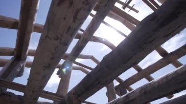 Mavi bulutlu arka planda yuvarlak kütüklerden yapılmış tamamlanmamış ahşap evin alt manzarası. Şarjör. Marangozluk çalışıyor, yeni bir ev inşa ediyor..