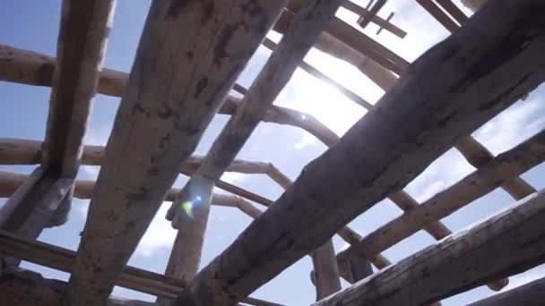 Κάτω όψη μέσα στο ημιτελές ξύλινο σπίτι από στρογγυλά κούτσουρα σε μπλε φόντο συννεφιασμένο ουρανό. Κλιπ. Εργασίες ξυλουργικής, ανέγερση νέου σπιτιού. — Αρχείο Βίντεο
