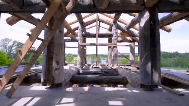 Vista all'interno di una costruzione in legno su cielo nuvoloso e sfondo alberi verdi. Clip. Casa in legno incompiuta realizzata in materiale ecologico . — Video Stock