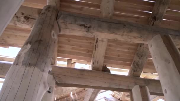 The master polishing the log of a wooden house frame, carpentry works. Clip. Bottom view of a man in white uniform and protective gloves with a grinding machine. — ストック動画