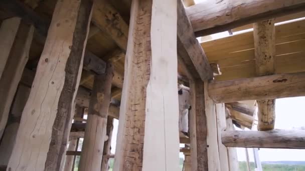 흰 제복을 입고 둥근 통나무로 만든 오두막집 의나무 벽을 닦고 있는 종업원. 클립. 건축 현장에서 맷돌로 일하는 목수. — 비디오