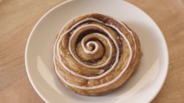 Cam bir tabakta yatarken dönen beyaz jöleli lezzetli çörek salyangozunun üst görüntüsü. Stok görüntüleri. Tatlı hamur işi ürününün kapanışı, gıda pornosu konsepti