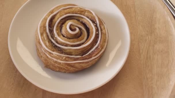 Ovanifrån av välsmakande bulle snigel med vit glasyr roterande medan liggande på en glasplatta. Lagerbilder. Närbild av söta bakverk produkt, food porn koncept — Stockvideo