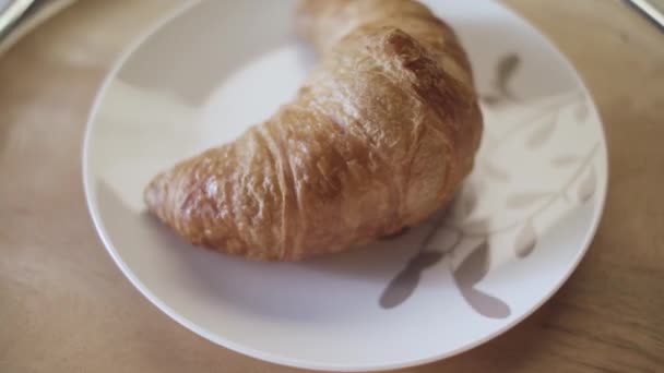 Französische Croissants auf einem Teller, aus nächster Nähe. Archivmaterial. köstliche frisch gebackene knusprige Croissant liegt auf dem Teller auf Holztischhintergrund. — Stockvideo