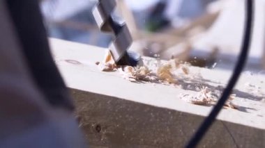 Marangoz matkapla ahşap kirişte delik açar, el işi konsepti, ahşap işçiliği. Şarjör. Çalışan matkabı ahşap talaşıyla kapatın..