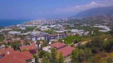 Sahile, gök mavisi denize ve sahile uzanan güzel tepelerin havadan manzarası. Şarjör. Küçük yeşil kıyı kasabası Avrupa 'nın en popüler tatil beldesidir..