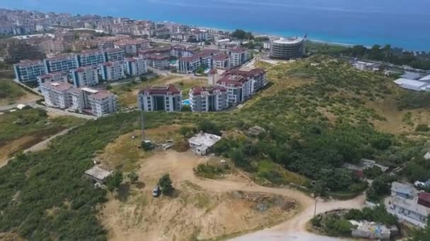 Vista aérea de la ciudad costera en Grecia. Art. Muchos edificios y casas construidas en la zona montañosa frente al azul hermoso mar en un día soleado de verano . — Vídeos de Stock