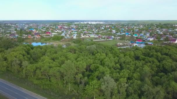 Panoramische Luftaufnahme der schönen Kleinstadt und Umgebung mit Wiesen. Kunst. erstaunliche grüne Bäume und Felder mit einer kleinen Stadt dahinter. — Stockvideo