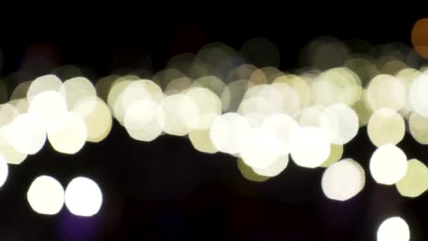 Defocated beige lichten bewegen langzaam op zwarte achtergrond. Actie. Stromende bokeh heldere cirkels van licht in het donker, wazig achtergrond. — Stockvideo