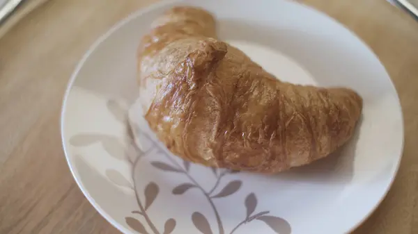 Croissants franceses em um prato, perto. Imagens de stock. Delicioso croissant croissant crocante acabado de fazer no prato em fundo de mesa de madeira . — Fotografia de Stock