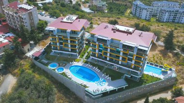 Tepenin tepesinde, büyük bir yüzme havuzu, tatil ve yaz seyahati konsepti olan lüks bir otel havası. - Sanat. Yeşil sahil şehrinin en üst manzarası.