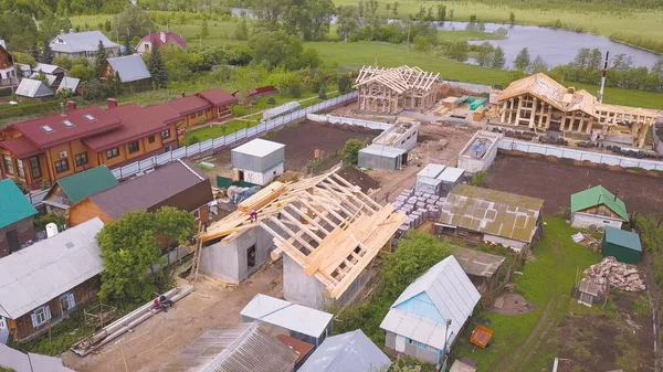 Shora dolů letecký pohled na dům ve výstavbě s dřevěným rámem. Klip. Ekologický dům během procesu výstavby obklopený obcí. — Stock fotografie