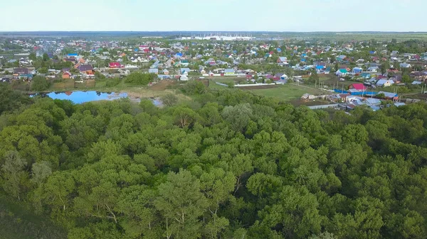 Panoramatický letecký výhled na krásné malé město a okolí s loukami. Umění. Úžasné zelené stromy a pole s městečkem vzadu. — Stock fotografie