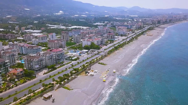 Stunning view from above of the city located along the sea shore and sandy beach. Art. Aerial top view of city center coastline with embankment and the road wih driving cars. — Stock Photo, Image